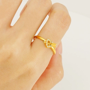 Macro detail of adjustable golden heart and arrow ring with sparkling pave crystals