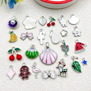 Flat lay of colorful enamel fruit and animal charms on a white textured background