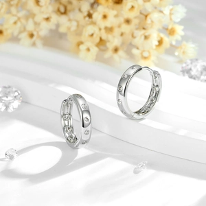 Classic silver geometric hoop earrings with micro-set zircon stones on white marble stairs