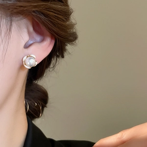 Dettaglio degli orecchini a fiore con perle e smalto bianco indossati per un look retrò
