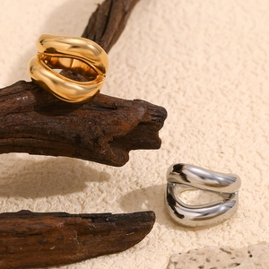 Detail of chunky wavy rings in 18K gold and silver finishes on a wooden branch