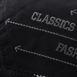 Detailed macro view of black twill fabric with grey Classics and Fashion embroidery