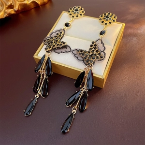Detail of vintage gold bow earrings with black crystal tassels on a luxury jewelry box