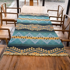 Detail of woven boho picnic blanket with geometric patterns and fringe on a wooden table
