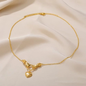18K gold-plated necklace with interlocking hands and heart pendant on silk background