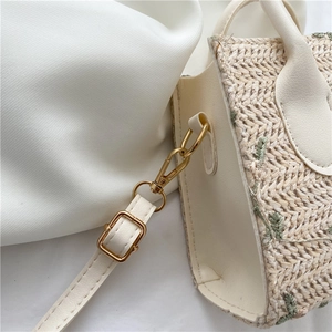 Straw woven crossbody bag with white leather trim and floral detail for summer