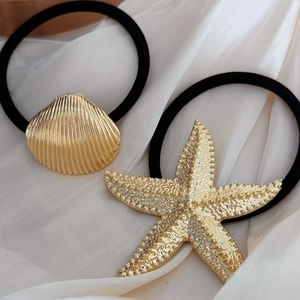 Gold starfish and seashell hair ties with black elastic band on silk background
