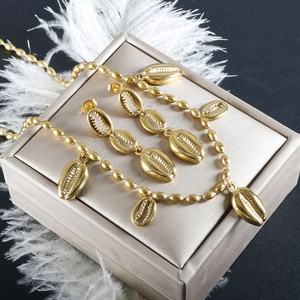 Detail of gold conch shell jewelry set including necklace and earrings on silk box