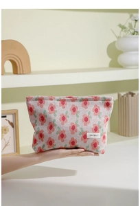 Detail of knitted makeup bag with red floral pattern and brand woven label on soft side