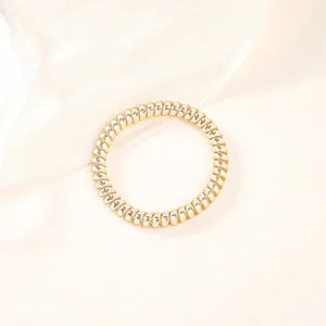 Macro view of a champagne gold spiral phone cord hair tie on elegant silk fabric