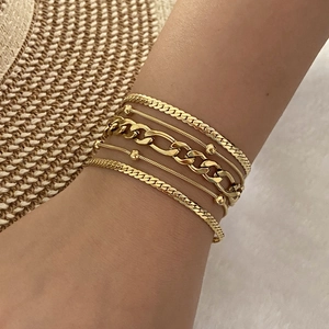 Set of five gold stainless steel bracelets with snake and curb chains on female wrist