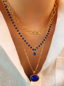 Close-up of three-layer layered necklace featuring blue beaded chain and gold pendants