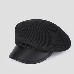 Detail of black woven newsboy cap featuring a smooth faux leather brim and textured crown