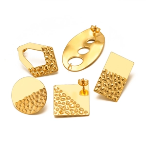 Detailed view of golden geometric earring studs with polished and hammered textures