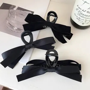 Close-up of elegant black velvet and satin bow hair claws on a stylish background