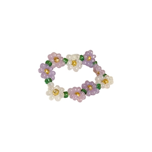 Handmade beaded flower ring in purple and white with golden core and green accents