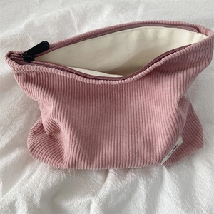 Pink corduroy makeup bag with black zipper detail and soft off-white canvas lining
