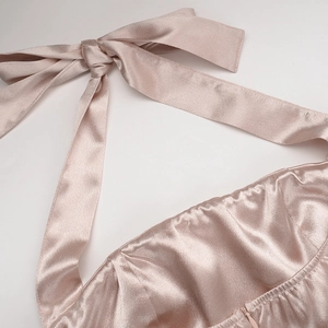 Détail du nœud licou et de la texture satinée plissée sur la robe de couleur champagne clair