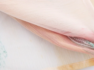 Gros plan sur la texture du tissu rose avec détail de couture surjetée jaune