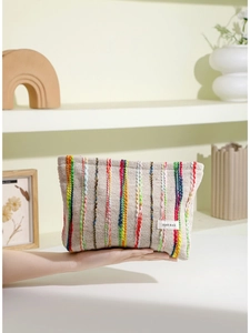 Trousse de maquillage rayée à grande capacité tenue à la main dans un décor doux