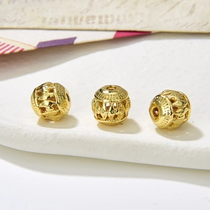 Macro shot of three vintage hollow gold metal beads with detailed relief patterns for DIY jewelry