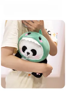 Close-up of a panda plush toy wearing a green dinosaur hood with soft fleece texture