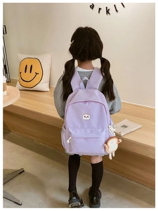 Cute purple children backpack with a cat patch and toast plush charm shown in a cafe