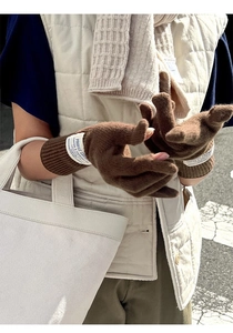 Close-up of brown wool knit gloves featuring detailed white textile cuffs and brand labels