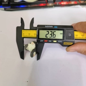 Digital caliper measuring the 23.6mm height of a cute black and white sitting cat figurine