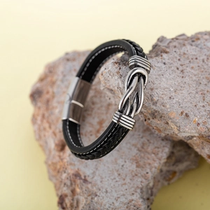 Men's black braided leather bracelet with silver knot metal buckle on natural stone