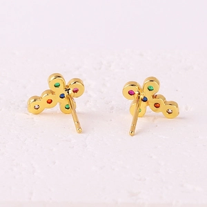 Gold plated floral cross earrings with colorful zircon stones on white texture