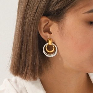 Close-up of model wearing two-tone triple-hoop earrings in gold and silver finish
