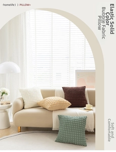 Detail of seersucker textured throw pillows in cream, green, and brown on a sofa