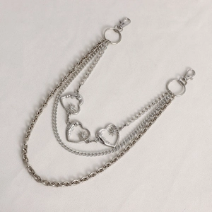 Detail of silver multilayer waist chain featuring heart and sun pendants for jeans