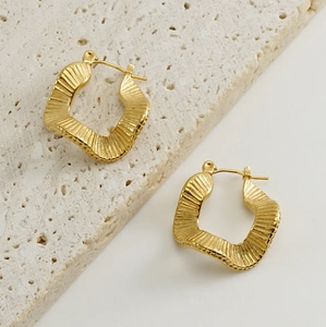 Detail of 18K gold-plated earrings with irregular wrinkled texture on stone pedestal