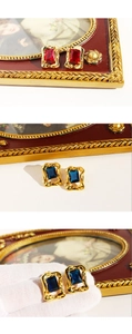 Macro detail of French vintage earrings with large square zircons and red enamel texture