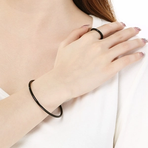 Close-up of minimalist black stainless steel bangle and matching ring set on a model
