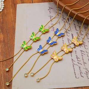 Close-up of gold snake chains with colorful butterfly pendants on vintage paper
