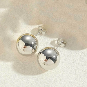 Macro detail of polished silver ball stud earrings with glossy mirror finish and butterfly back