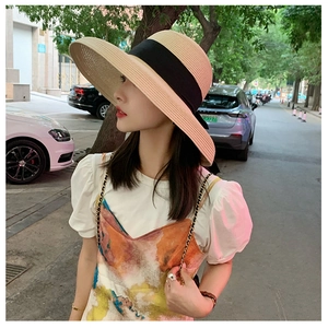 Detalle de un sombrero de paja de ala ancha con cinta negra, estilo elegante de verano