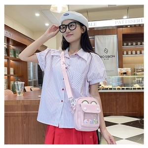 Pink crossbody ita bag with clear window and adjustable strap shown in cafe setting