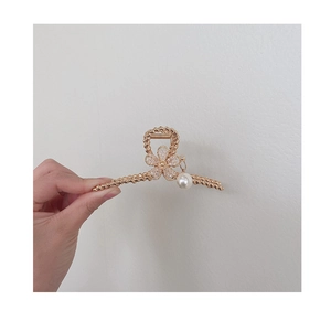 Detail of golden metal hair claw clip with crystal flowers and a hanging pearl charm