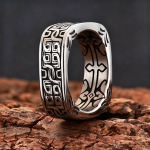Macro shot of wide square ring with vintage totem patterns on brushed silver metal