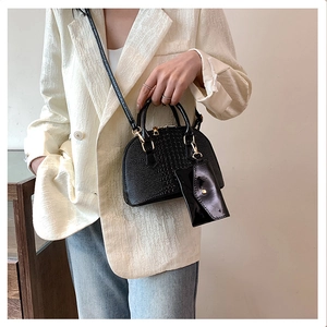 Detail of black crocodile texture shell bag with mini coin purse on a fashion model