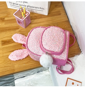 Close-up of pink sequined backpack with rabbit ears and a white plush pompom charm