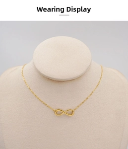 Detailed view of a delicate gold infinity pendant necklace on a jewelry display stand