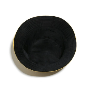 Dettaglio del cappello a secchiello bicolore in twill di cotone nero e tesa gialla
