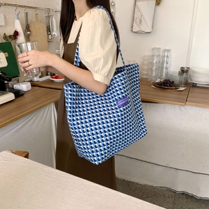 Detail of blue and white checkered canvas tote bag with purple woven label and large capacity