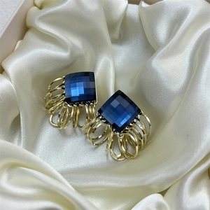 Elegant gold layered ring earrings featuring a square blue crystal on silk fabric