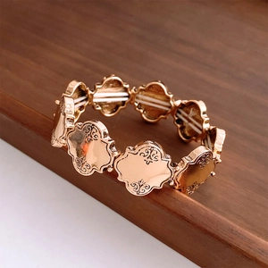 Detail eines roségoldenen Stretch-Armbands mit Vintage-Blumenmustern auf den Metallgliedern
